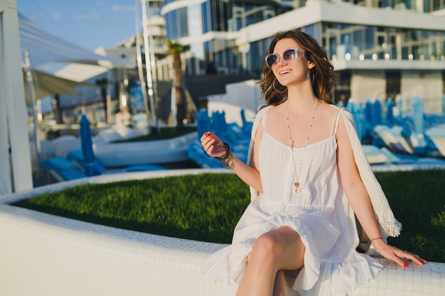 woman in white dress at summer resort hotel, wearing sunglasses and stylish accessories