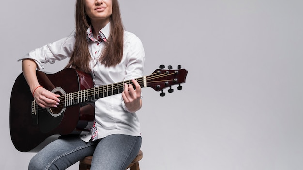 Woman in white shirt playing the guitar