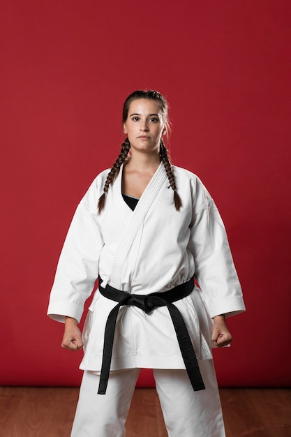 Woman in white uniform and black belt looking at camera