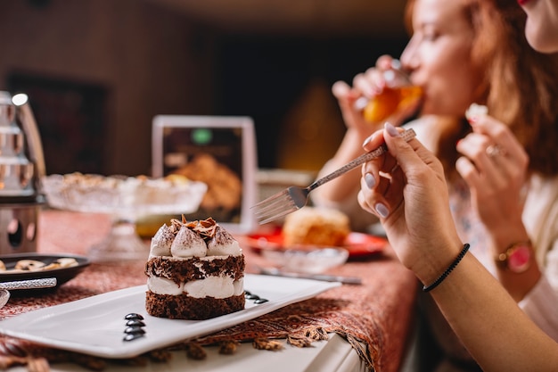 Woman will eat portioned layered cacao cake with white cream and chocolate pieces