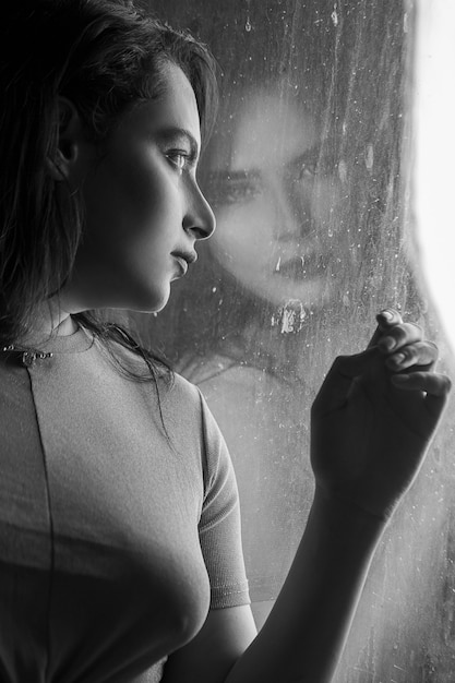 Woman in window looking to the rain, black white photo