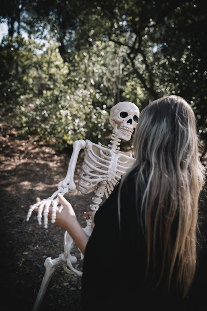 Woman in witch costume bending skeleton