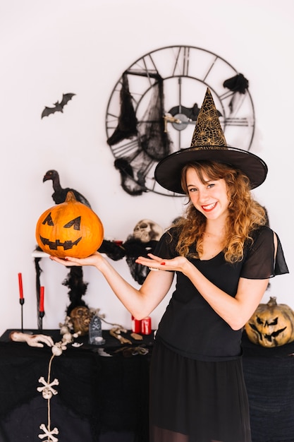 Free Photo woman in witch costume holding pumpkin and smiling