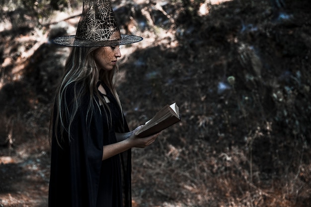 Free Photo woman in witch costume reading book 