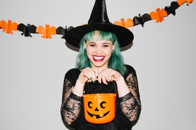 Free Photo woman in witch hat with pumpkin bag