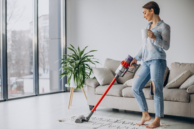 Free photo woman with accumulator vacuum cleaner drinking coffee