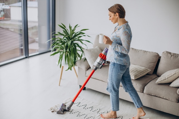 Woman with accumulator vacuum cleaner drinking coffee