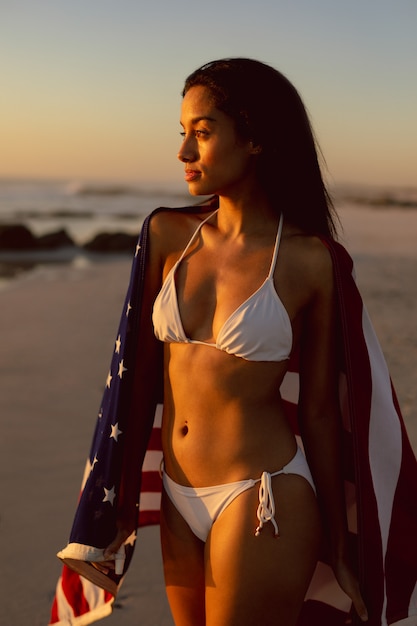 Woman with an American flag standing on the beach