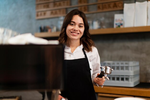 Woman with apron posing with coffee machine component