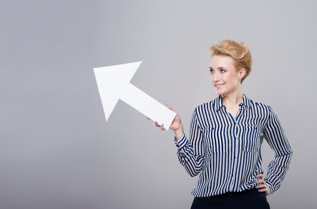 Free photo woman with an arrow on grey background