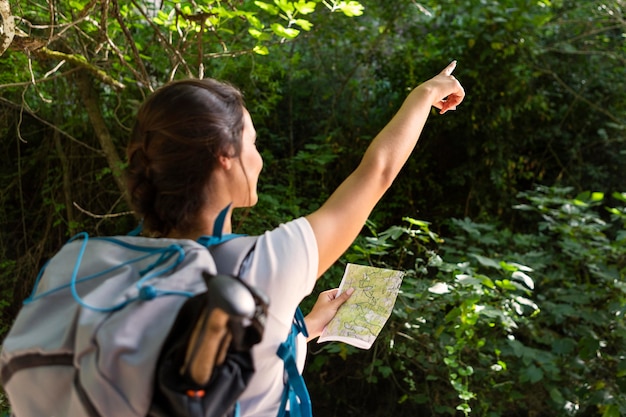 Woman with backpack pointing while holding map