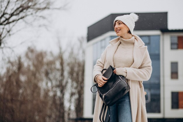 Woman with bag wearing winter coat walking in the street