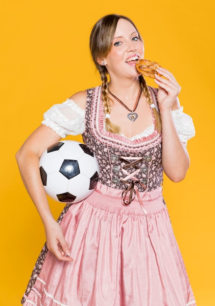 Free photo woman with ball eating a pretzel