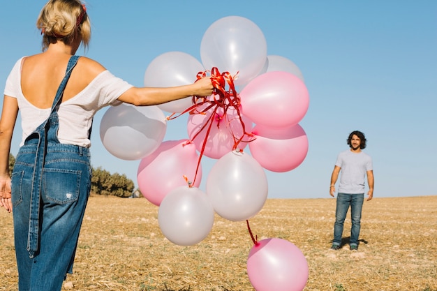 Free photo woman with balloons walking towards man