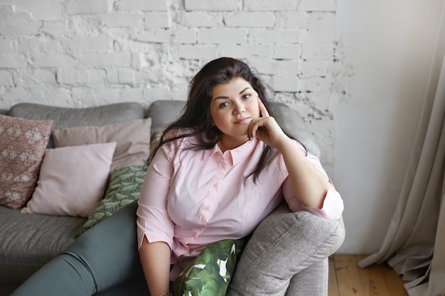 A woman with beautiful body is posing on the couch