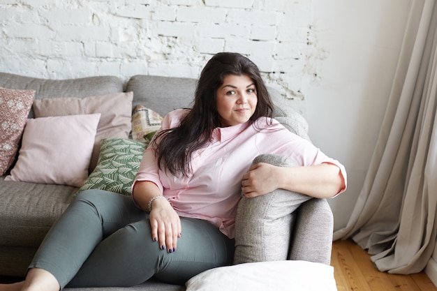 A woman with beautiful body is posing on the couch