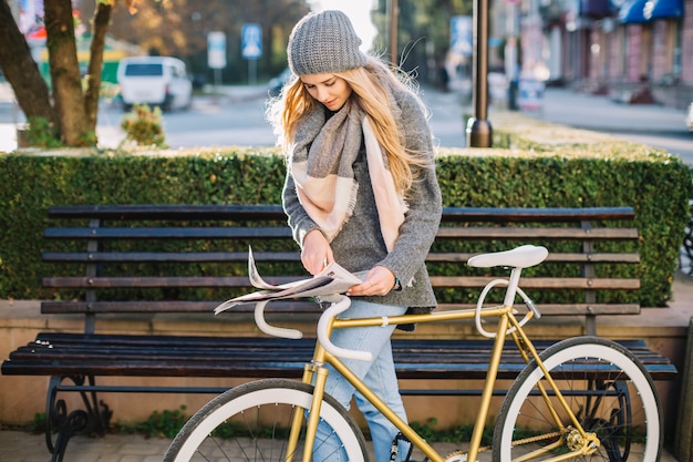 Woman with bicycle searcing information in newspaper