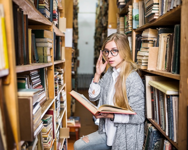 Free Photo woman with book adjusting glasses