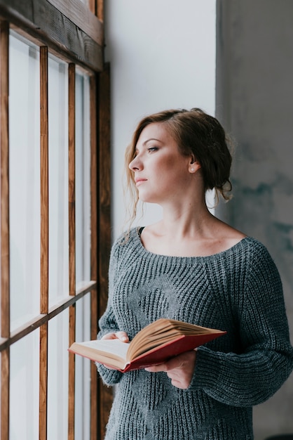 Woman with book looking out window