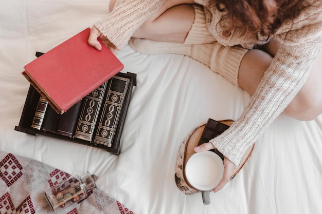 Woman with book and milk on bed