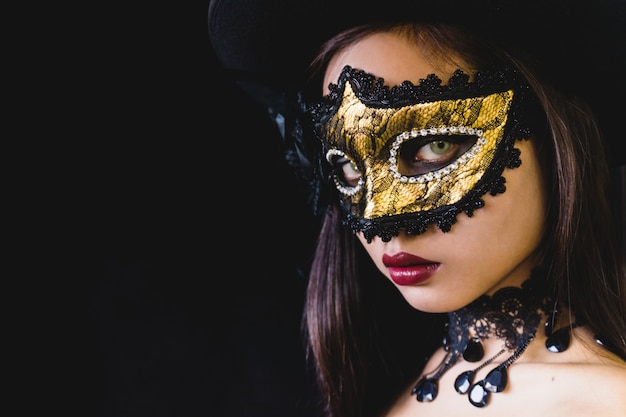 Woman with a carnival mask on a dark background