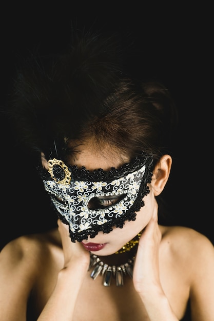 Free Photo woman with a carnival mask on a dark background