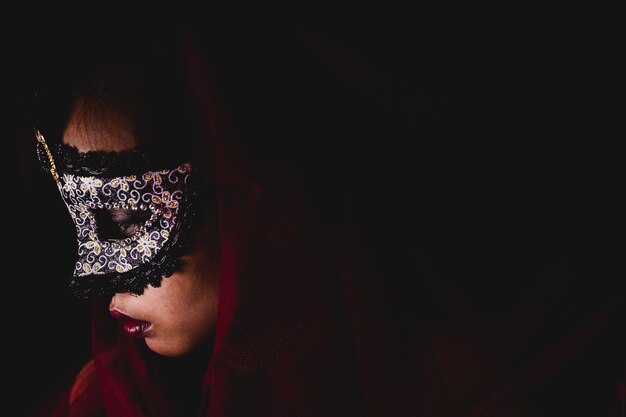 Woman with a carnival mask on a dark background