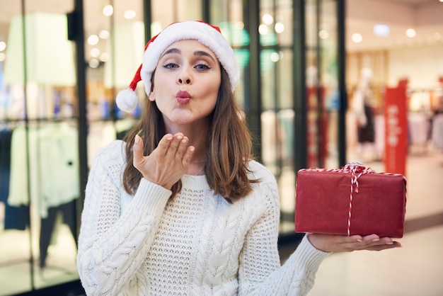 Woman with Christmas present blowing a kiss