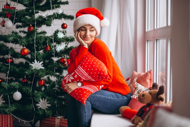 Woman with Christmas presents by Christmas tree