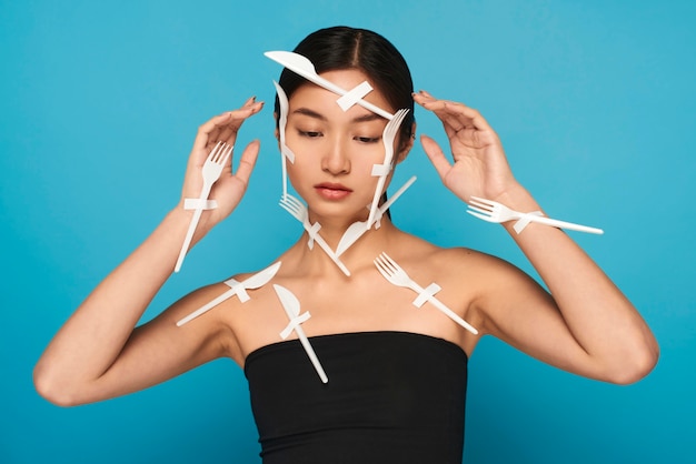 Free photo woman with closed eyes being covered in plastic white tableware