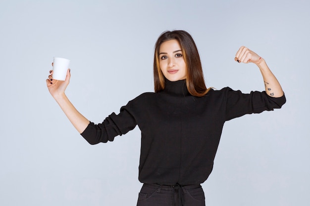 Free photo woman with a coffee cup showing her muscles.