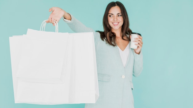 Free Photo woman with coffee and shopping bags on a blue background