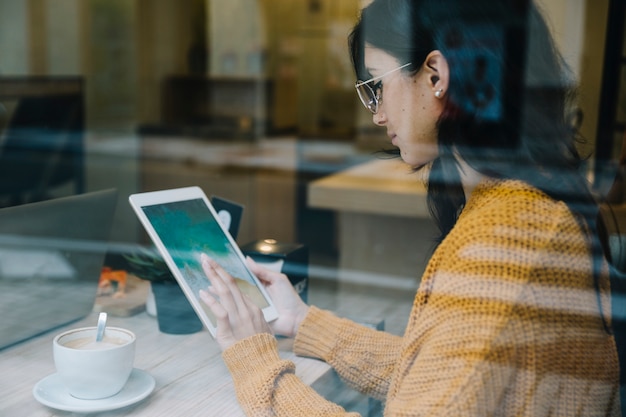 Free Photo woman with coffee tapping tablet screen