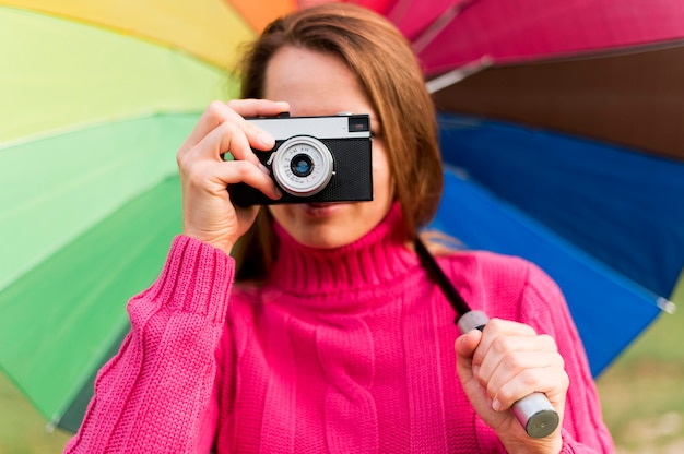 Free photo woman with colorful umbrella taking a photo with her camera