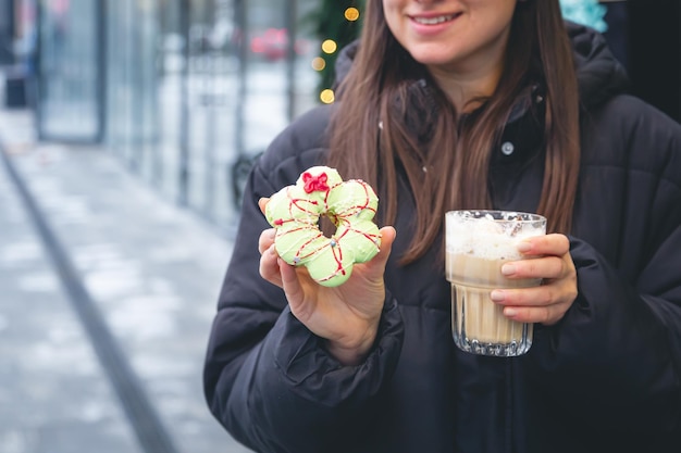 Free photo woman with a cup of coffee and christmas macaroon outside in winter