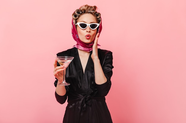 Free photo woman with curlers in surprise poses on pink wall