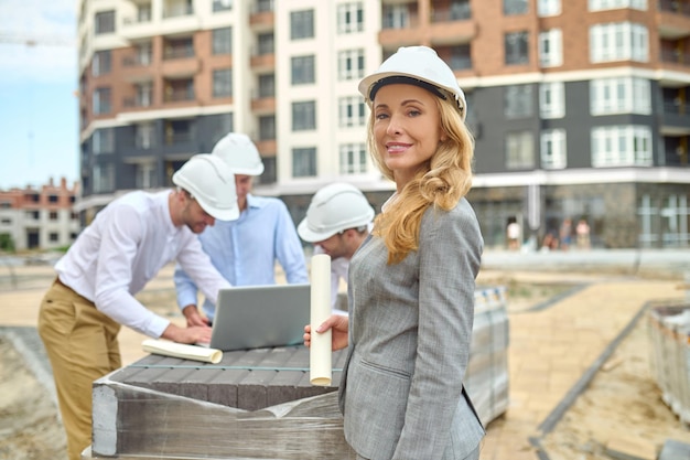 Woman with drawing and men with laptop behind outdoors