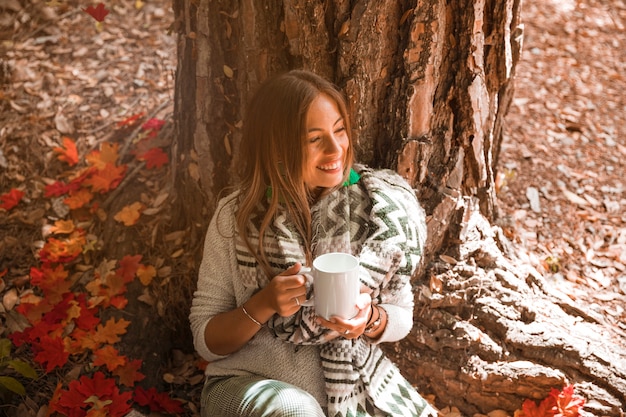 Free photo woman with drink enjoying weather in autumn forest