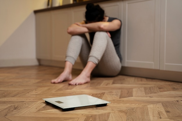 Free photo woman with eating disorder crying next to a scale