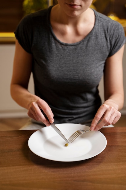 Woman with eating disorder having a pea on her plate