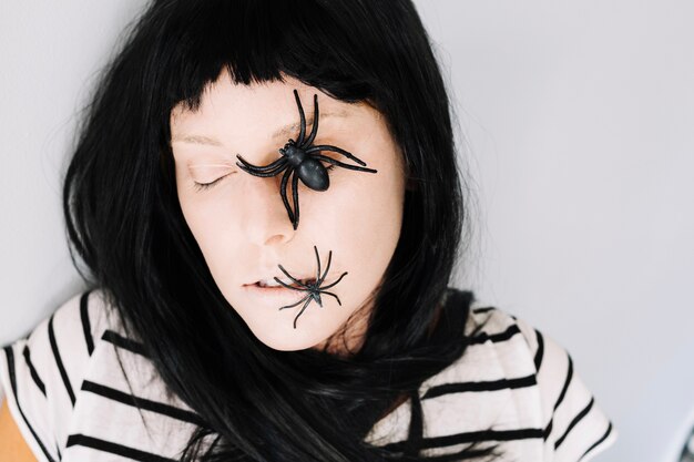 Woman with eyes closed and spiders on face