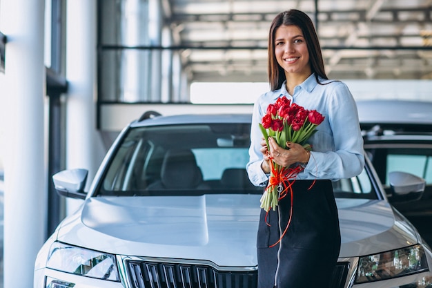 Free photo woman with flowers in a car showroom