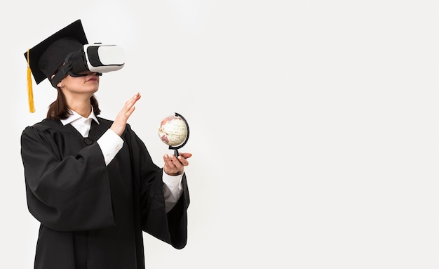 Free Photo woman with graduation robe and cap wearing virtual reality headset