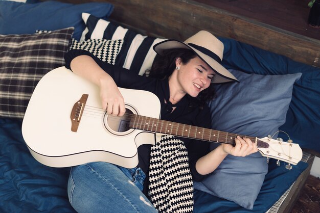 Woman with guitar on bed