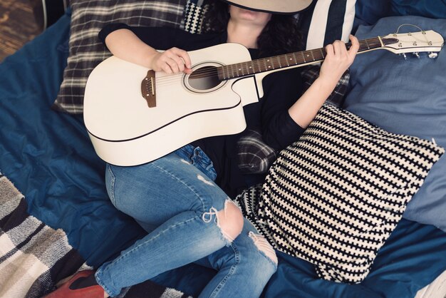 Woman with guitar in bed