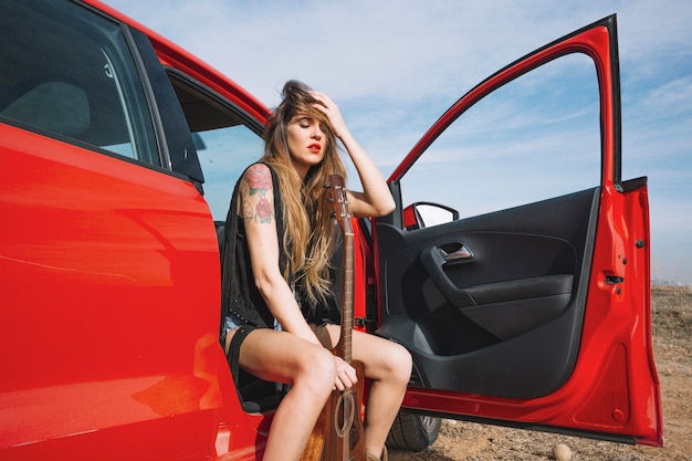 Woman with guitar sitting in car