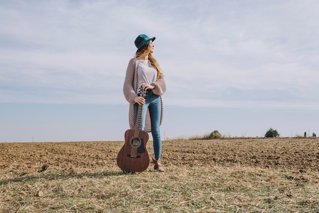 Free photo woman with guitar standing in field