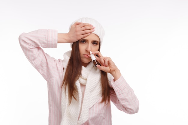 Free photo woman with a hand on her head and a nasal spray