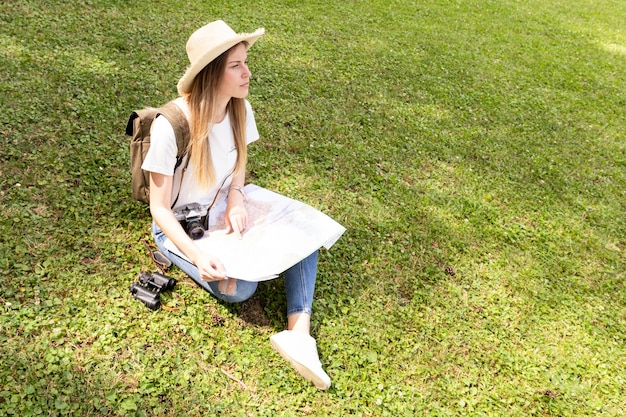 Woman with hat sitting on grass and looking away