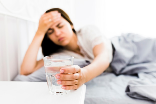 Woman with headache taking glass of water